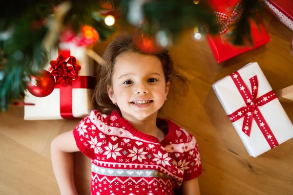 Petite fille couchée sous l'arbre de Noël parmi les cadeaux , — Photo