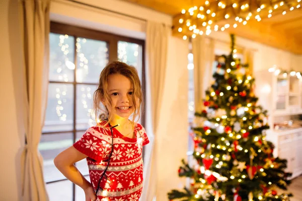 Mała dziewczynka dekorowanie choinki zaplątane w łańcuch światła. — Zdjęcie stockowe