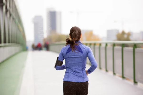 Junge Frau in der Stadt läuft auf grüner Stahlbrücke — Stockfoto