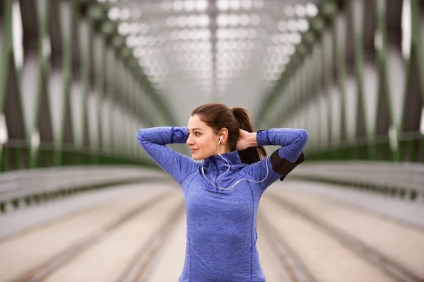 Young runner in the city stretching on green steel bridge — Stock Photo, Image