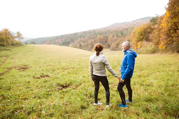 Hermosos corredores senior descansando fuera en la naturaleza soleada otoño — Foto de Stock