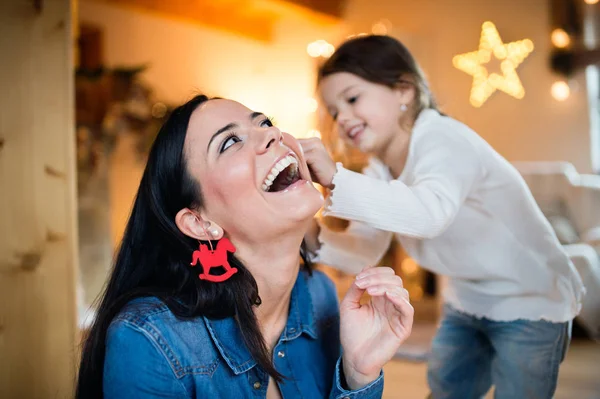 Ung mor med daugter dekorera julgran tillsammans. — Stockfoto