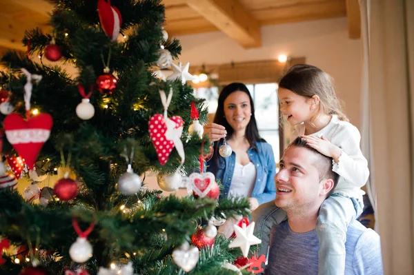 Mladá rodina s dcerkou na vánoční stromeček doma. — Stock fotografie