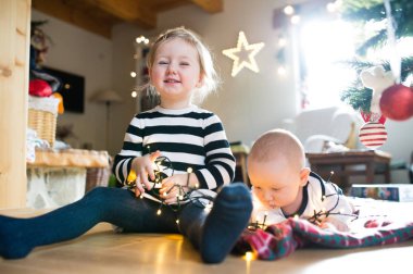 Erkek ve kız Noel ağacı ışıkları zincirindeki dolaşmış altında