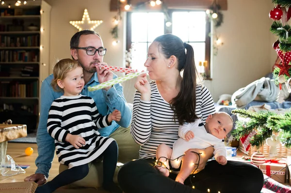 Pais com crianças na árvore de Natal soprando apitos festa — Fotografia de Stock