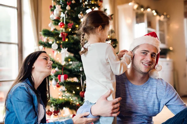 Família jovem com daugter na árvore de Natal em casa . — Fotografia de Stock