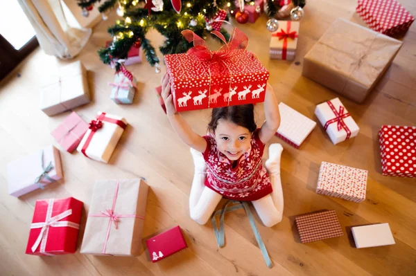 Little girl lying under Christmas tree among presents — Stock Photo, Image