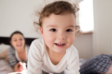 Anne ile kızı yatakta, yatarken eğleniyor