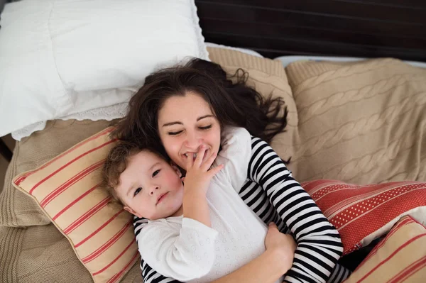 Mãe com sua filha deitada na cama, se divertindo — Fotografia de Stock