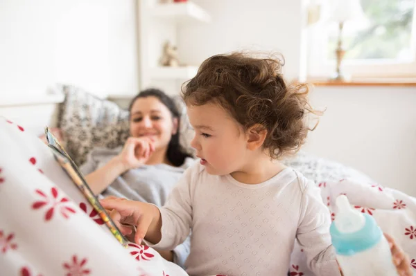 Ibu menempatkan putrinya untuk tidur, gadis membaca bukunya . — Stok Foto