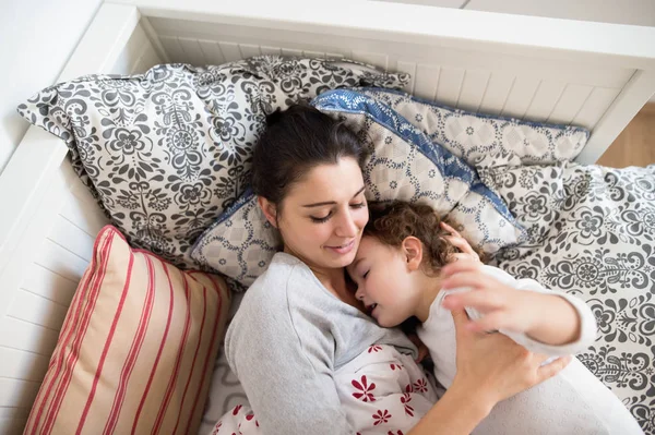 어머니, 침대에 누워 잠을 그녀의 작은 딸을 퍼 팅. — 스톡 사진