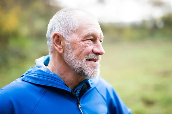 Senior runner in nature. Man resting, smiling. Close up.