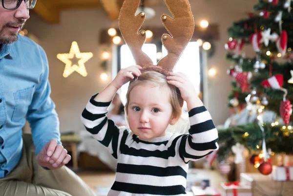 Father with daugter at Christmas tree, wearing reindeer antlers — Stock Photo, Image