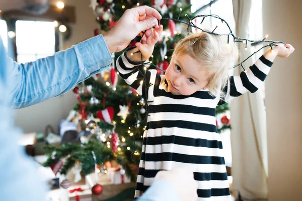 Father with daugter tangled up in light chain at Christmas tree. — Stock Photo, Image