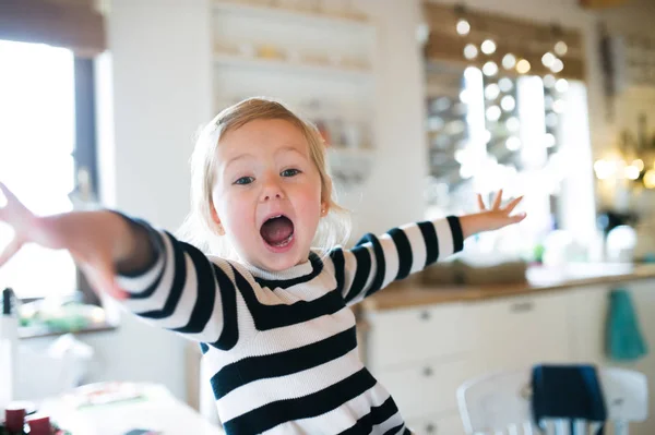 Linda niña en vestido a rayas sentado en la mesa de la cocina, shou —  Fotos de Stock