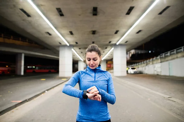 Молода жінка в блакитному светрі біжить в нічному місті — стокове фото