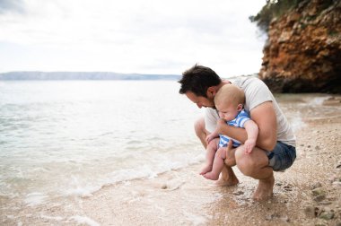 Adam plajda eğlenmek bebek oğluyla.