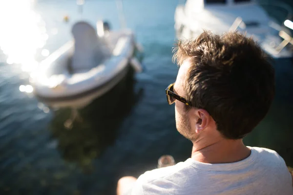 ชายที่มีความสุขกับเวลาที่ริมทะเล นั่งอยู่บนท่าเรือไม้ . — ภาพถ่ายสต็อก