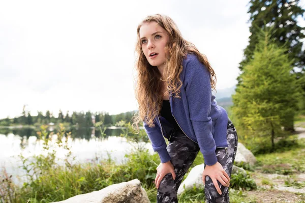 Schöne junge Läuferin am See in grüner Natur, die sich ausruht. — Stockfoto