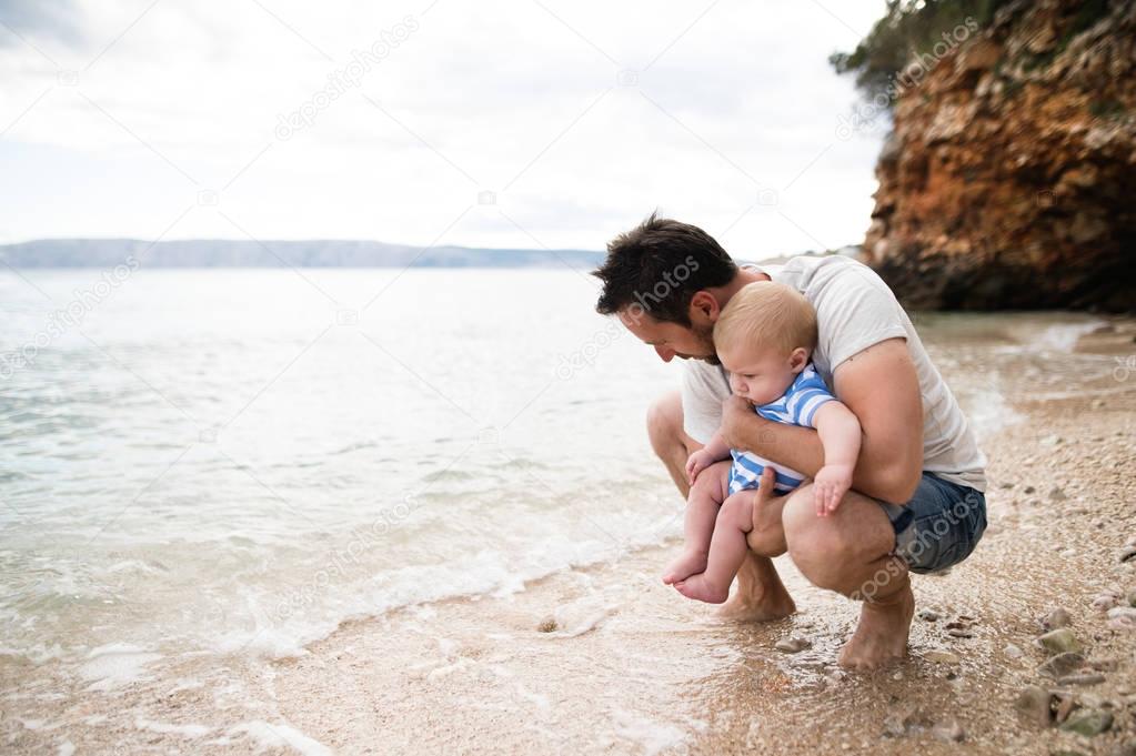 Man with his baby son at the beach having fun.