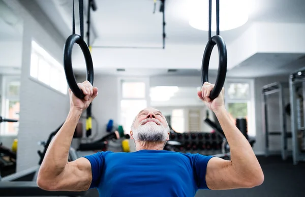 Hombre mayor en el gimnasio haciendo ejercicio en anillos gimnásticos — Foto de Stock
