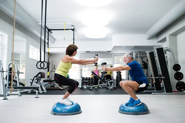 Äldre par i gymmet träna med vikter, huk — Stockfoto