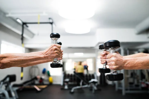 Manos de pareja mayor en el gimnasio haciendo ejercicio con pesas — Foto de Stock