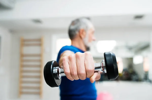 Uomo anziano in palestra che lavora con i pesi . — Foto Stock