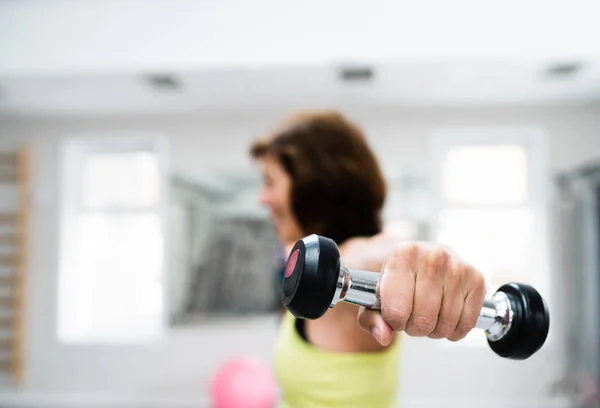 Femme âgée dans la salle de gym travailler avec des poids . — Photo