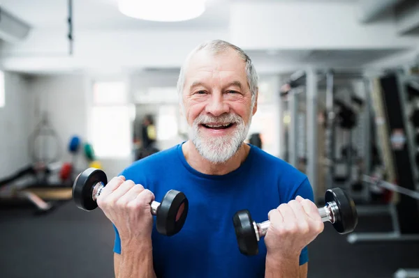 Senior man in gym working out with weights.