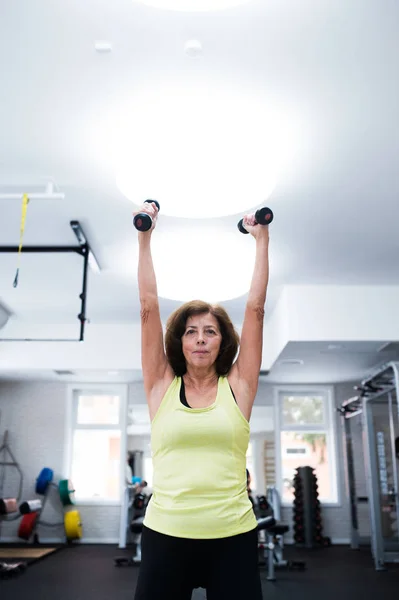 Seniorin trainiert im Fitnessstudio mit Gewichten. — Stockfoto