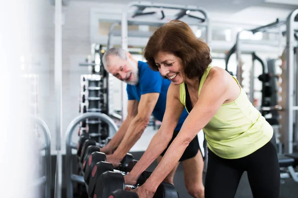 Pareja mayor en gimnasio haciendo ejercicio con pesas — Foto de Stock