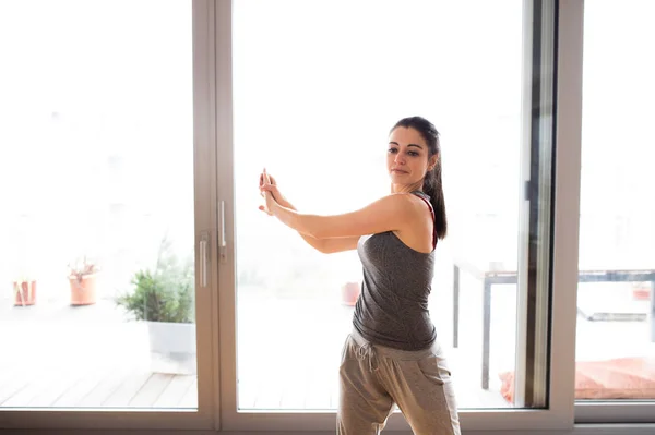 Junge Frau übt zu Hause, streckt die Arme aus. — Stockfoto