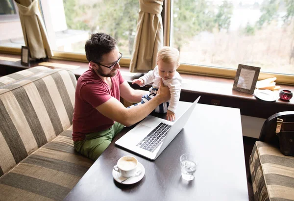 Hombre con cuaderno en la cafetería bebiendo café, sosteniendo a su hijo — Foto de Stock