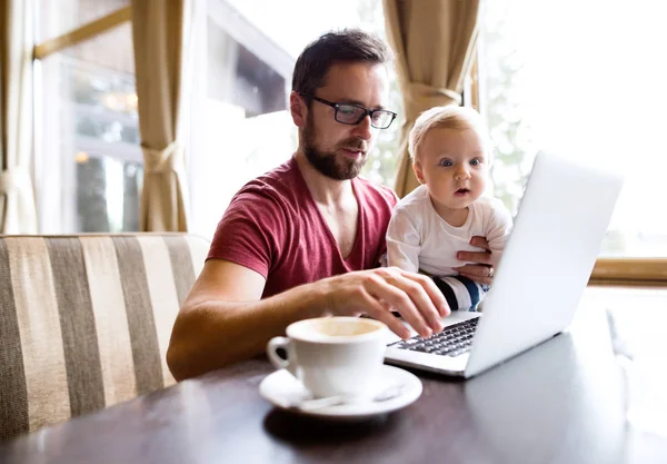 Man with notebook in cafe drinking coffee, holding his son — Stock Photo, Image