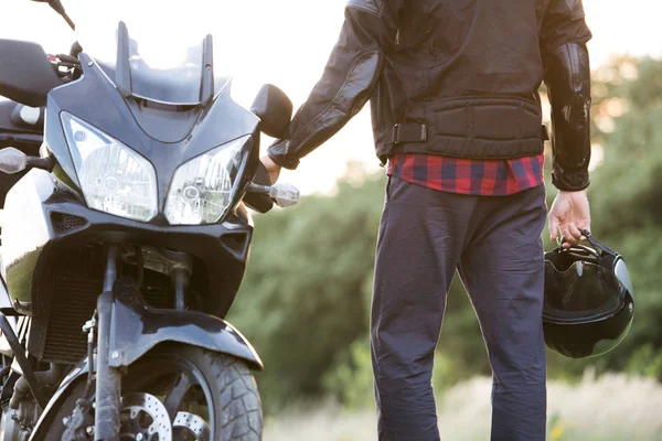 Unbekannter Mann steht auf dem Land an einem Motorrad. — Stockfoto