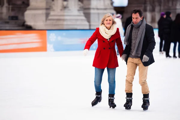 Casal sênior bonito patinação no gelo no centro da cidade. Inverno — Fotografia de Stock