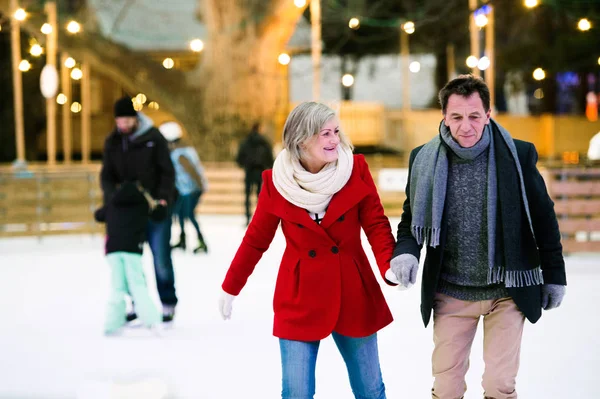 Casal sênior bonito patinação no gelo no centro da cidade. Inverno — Fotografia de Stock