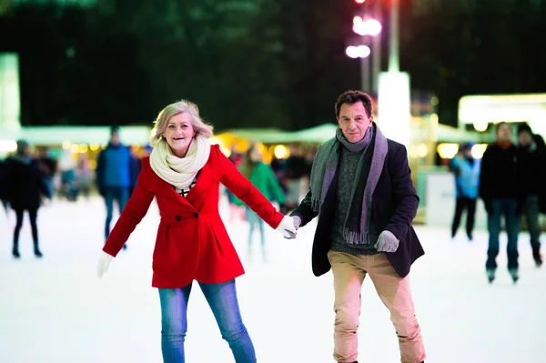 Casal sênior bonito patinação no gelo no centro da cidade. Inverno — Fotografia de Stock