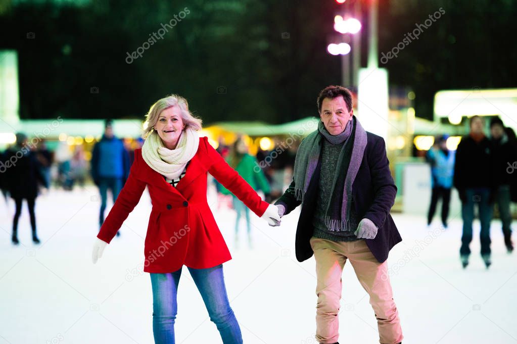 Beautiful senior couple ice skating in city centre. Winter