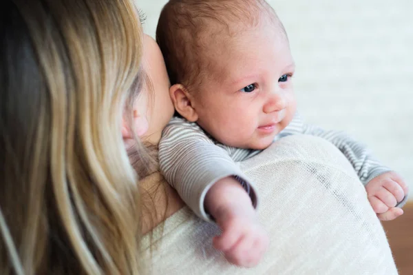 Irreconocible joven madre sosteniendo bebé hijo en sus brazos — Foto de Stock