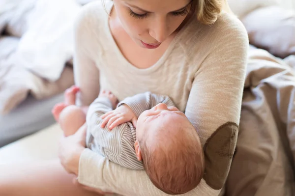 Hermosa madre joven sosteniendo al bebé en sus brazos —  Fotos de Stock