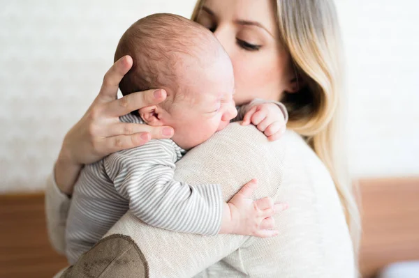 Die schöne junge Mutter hält ihren kleinen Sohn auf dem Arm — Stockfoto