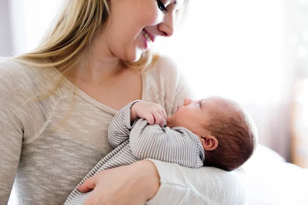 Die schöne junge Mutter hält ihren kleinen Sohn auf dem Arm — Stockfoto