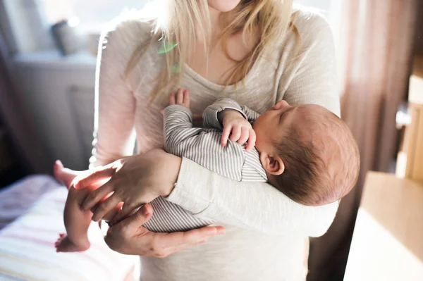 Onherkenbaar jonge moeder zoontje in haar armen houden — Stockfoto