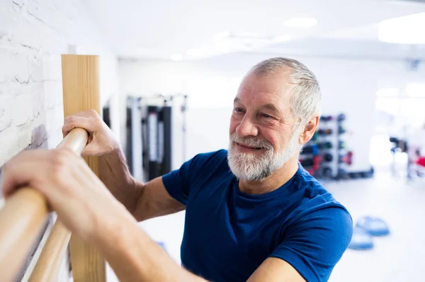 Äldre mannen i gym tränar på vägg barer. — Stockfoto