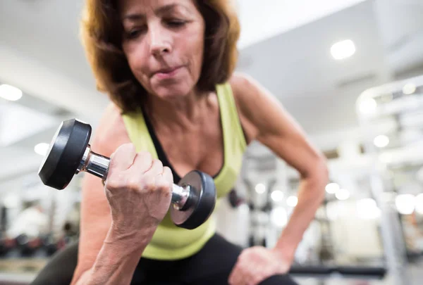 Femme âgée dans la salle de gym travailler avec des poids . — Photo