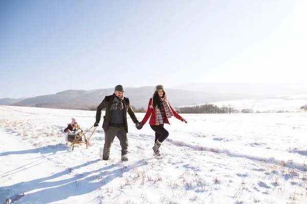 Father and mother pulling daughter on sledge, running. Winter na — Stock Photo, Image