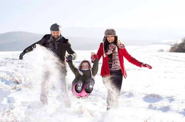 Vader en moeder met hun dochter, spelen in de sneeuw. — Stockfoto