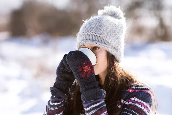 Beautiful young woman with cup of coffee in winter nature — Stock Photo, Image